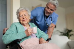 Older adult reviewing a medication schedule with a caregiver at a dining table.